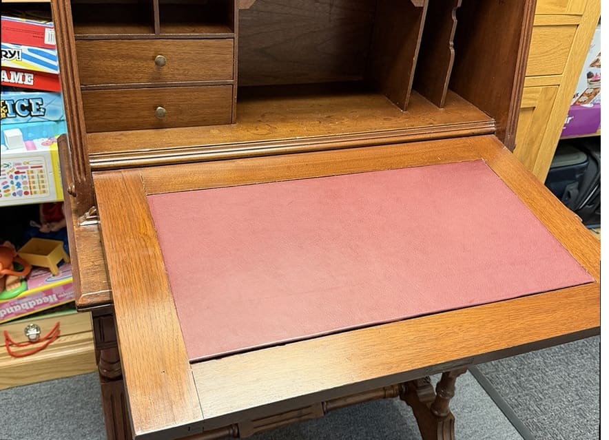 The same antique desk after refinishing, with restored wood and a new leather writing surface