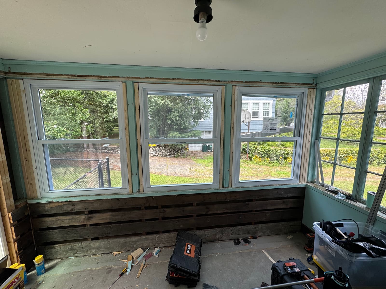 A sunroom wall opened up with fresh drywall compound and new trim during repairs