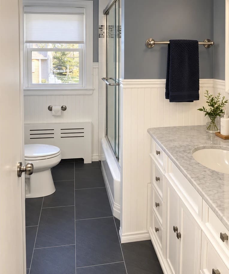 A renovated bathroom with large dark floor tile and a white vanity