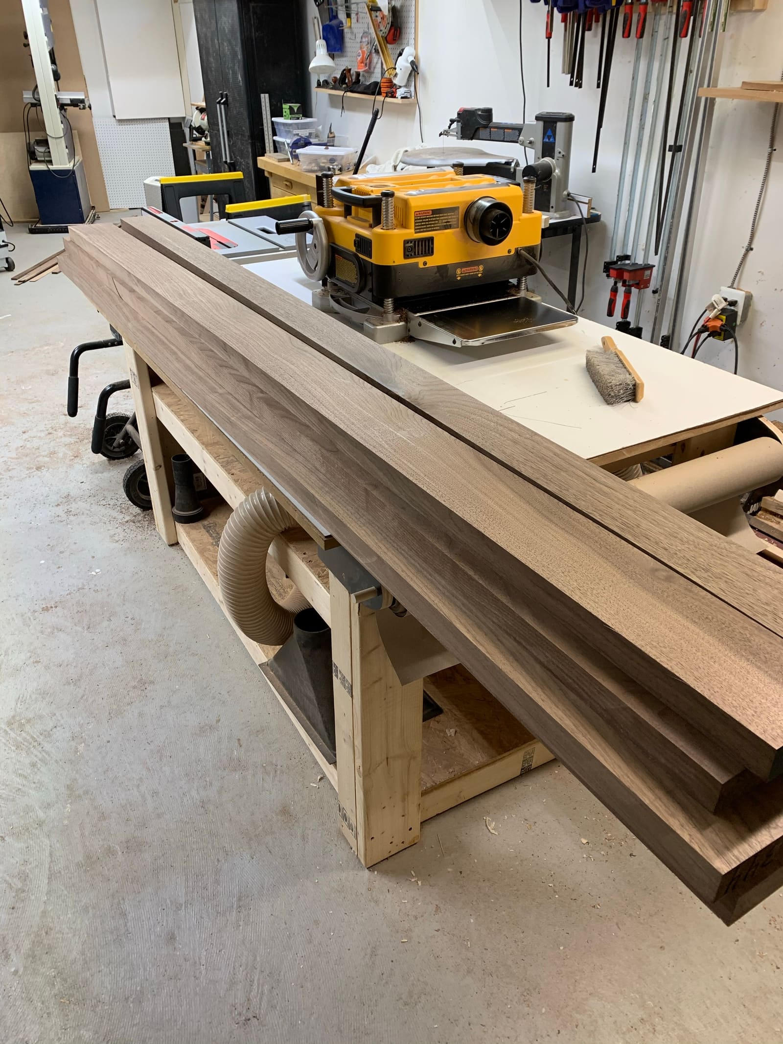 Walnut boards being planed flat on a workbench in the shop